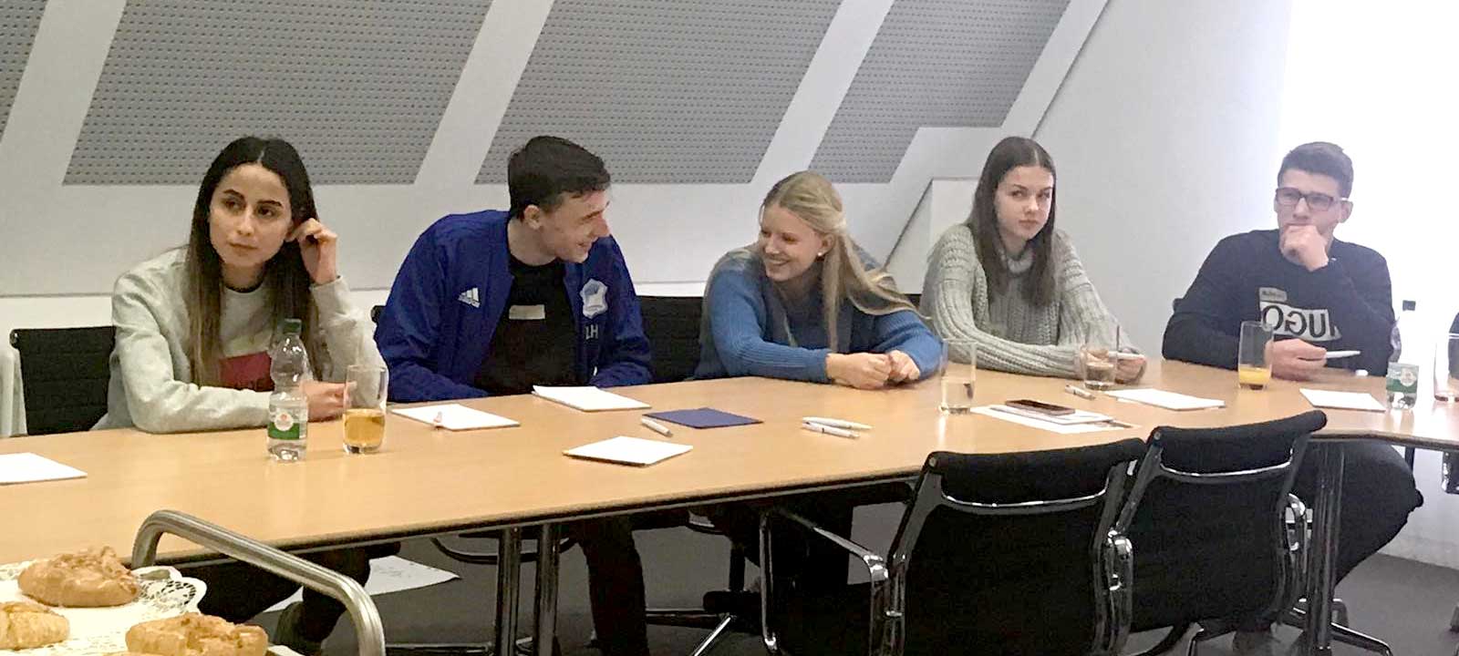 Schüler sitzen im Rechteck an Tischen