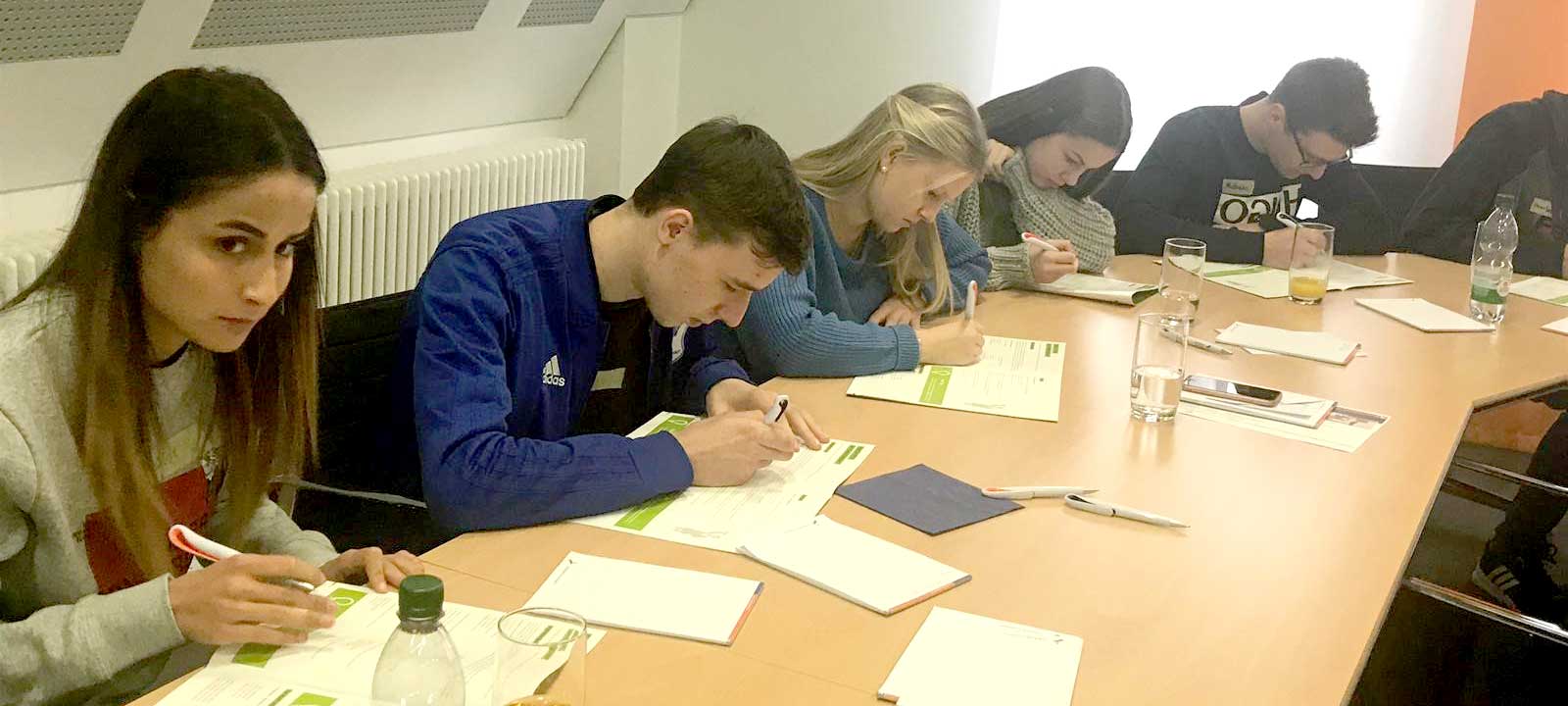 Schüler sitzen im Rechteck an Tischen