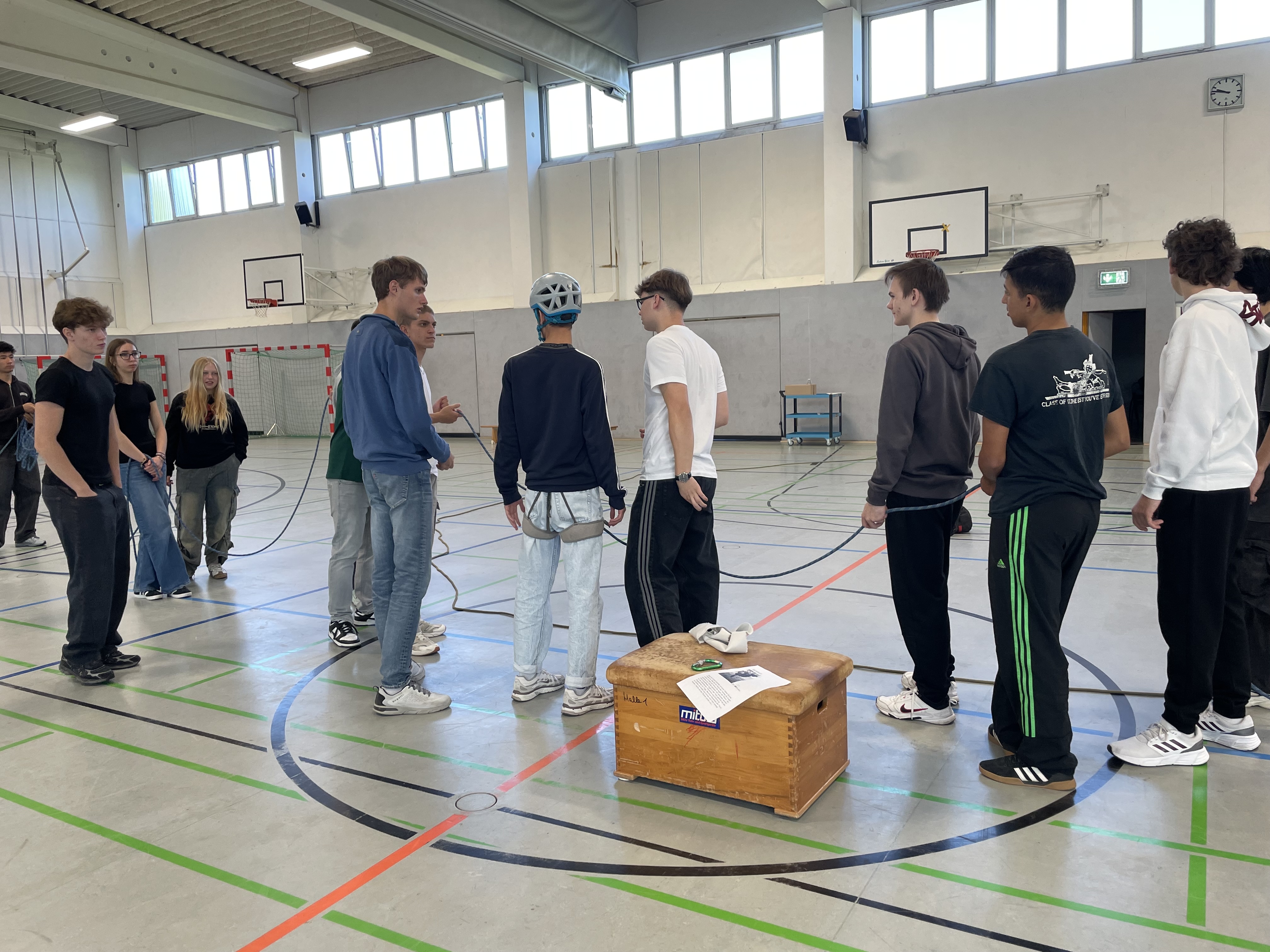 Schülerinnen und Schüler mit Seil, eine Person mit Helm und Gurten