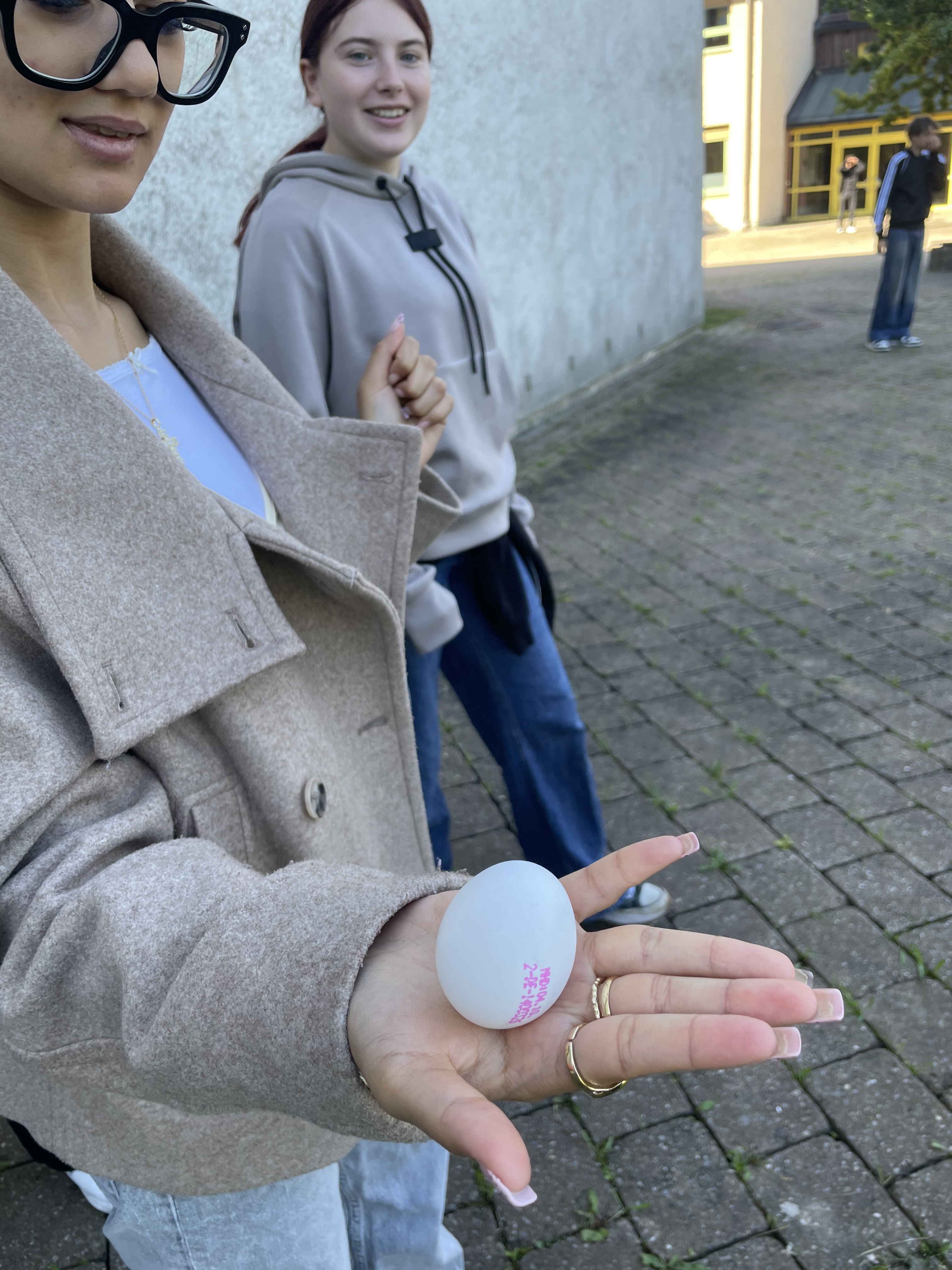 Zwei Schülerinnen, eine zeigt ein Ei