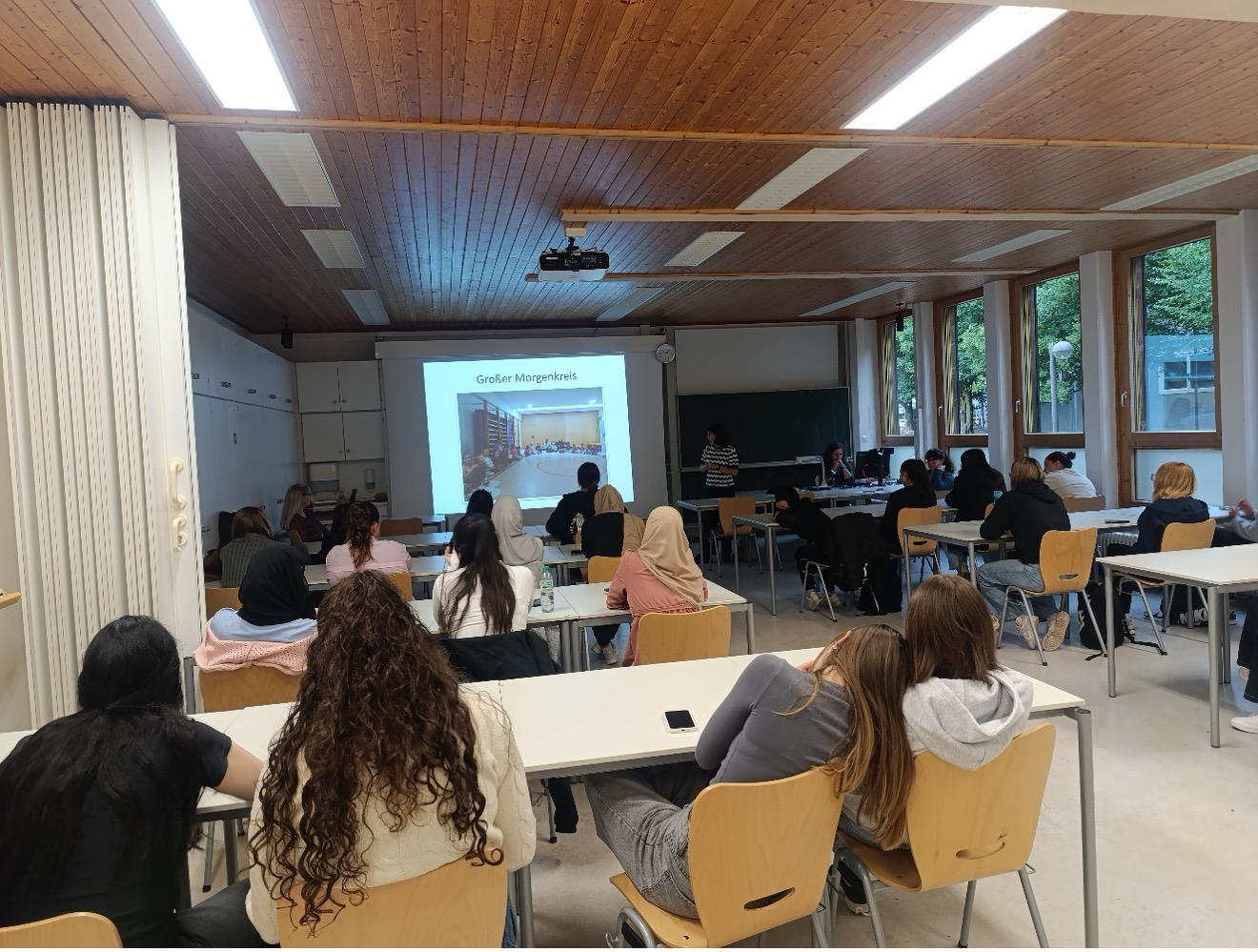 Lernende sitzend in Klassenzimmer, Beamer