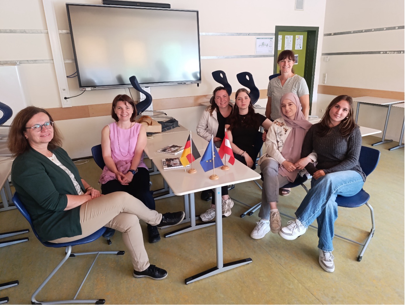 Lehrkräfte und Lernende sitzend mit Länderfahnen