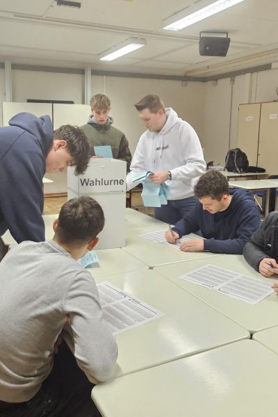 Mehrere Schüler mit Stimmzettel, Wahlurne