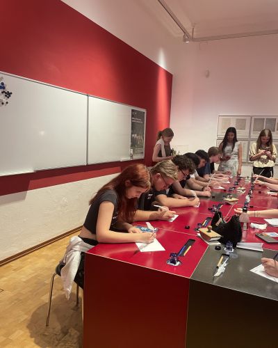Schülergruppe sitzend und mit Feder und Tinte schreibend