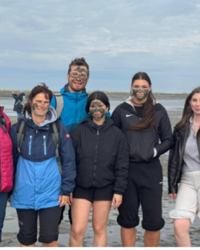 Schülergruppe bei Wattwanderung teils mit Schlick im Gesicht