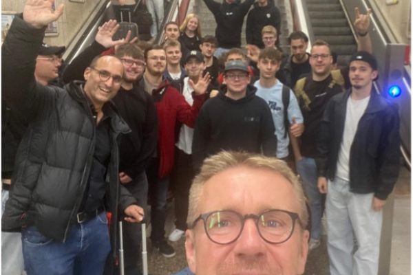 Jugendliche und Lehrkräfte stehend vor Rolltreppe