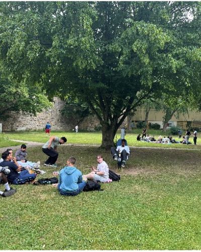 Schüler scannen den QR Code von einem Themenschild; Hintergrund  ist Bebauung zu sehen