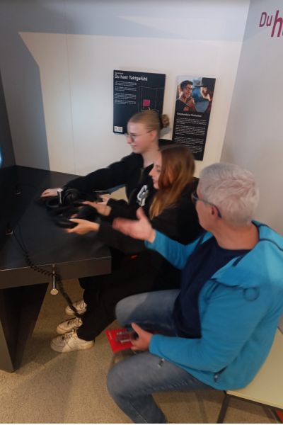 Schülerinnen und Lehrkraft sitzend vor PC