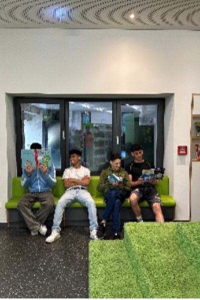 Vier Personen sitzend und z. T. lesend