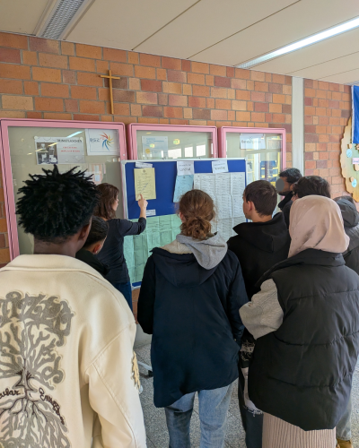 Lernende vor Infowand mit Wahlzetteln