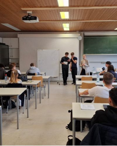 Vortragende, stehend, und Lernende, sitzend